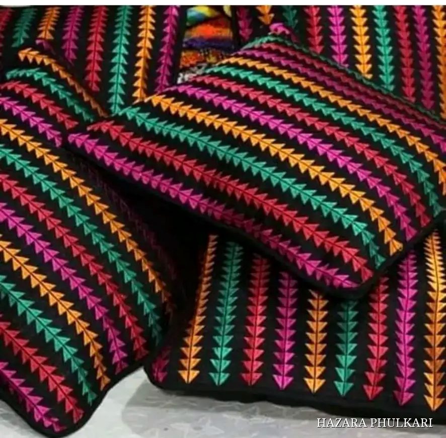 A set of handmade Phulkari cushion covers embroidered in orange, green and magenta chevron stripes on black fabric