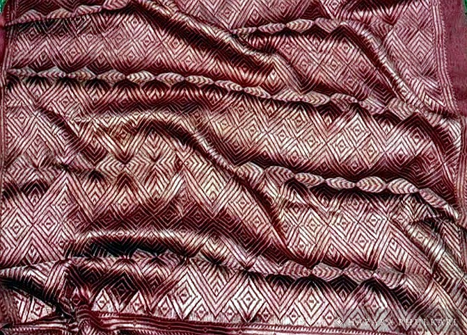 Close detail of tonal red embroidery where the stitch direction creates the pattern