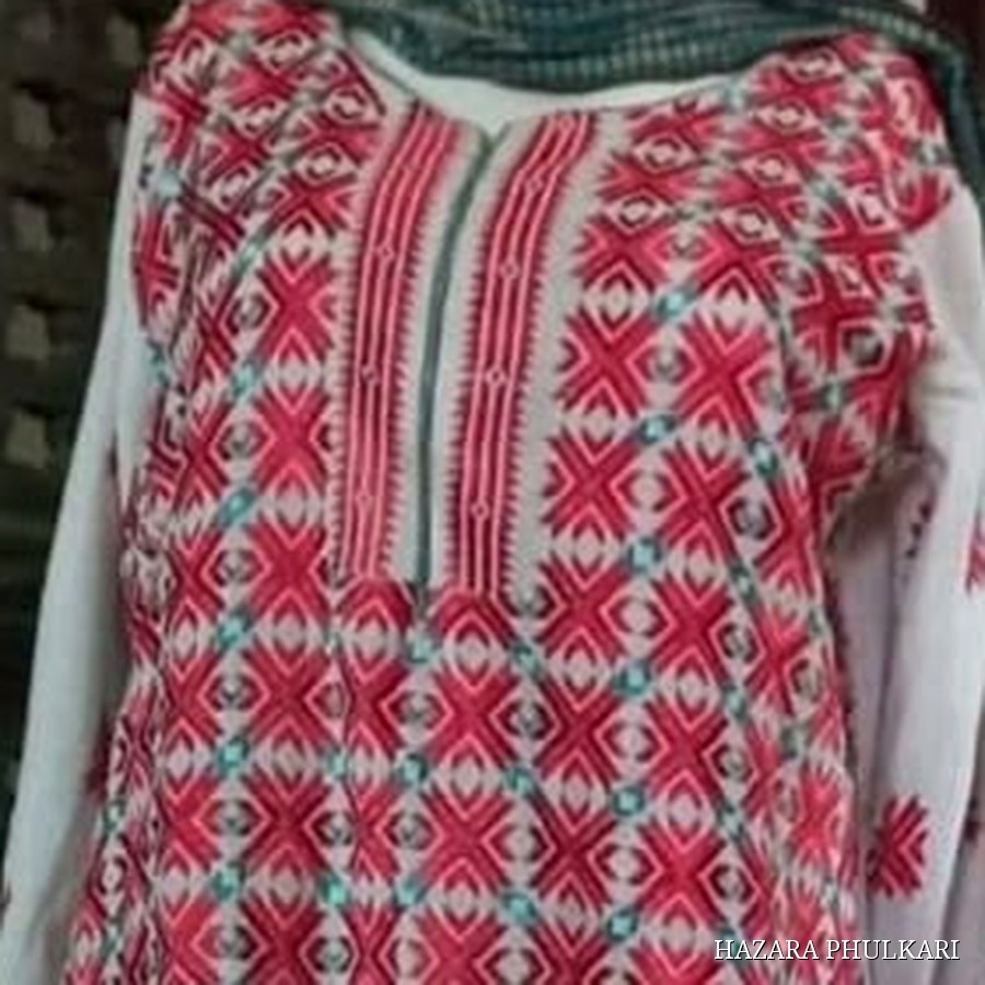 Close detail of a Phulkari shirt neckline showing counted-thread red and turquoise embroidery across the yoke