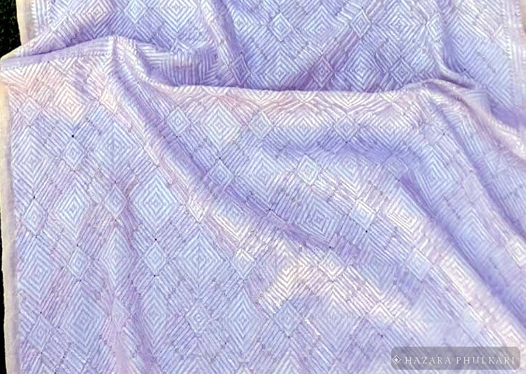 Texture detail of ivory embroidery thread worked across the weave of a natural fabric