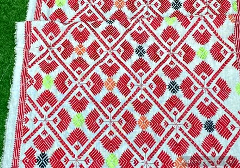Counted-thread Jasti Phulkari detail showing precisely aligned red, green and navy motifs