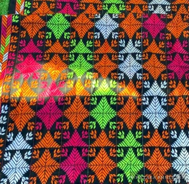 Detail of embroidered leaf and diamond motifs worked in orange, magenta and green thread